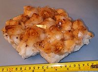 Oblique view of topaz cluster showing crystal coverage and measuring tape for scale