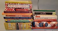 Two stacks of assorted cookbooks showing spines for title identification