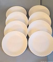 Front view of eight white scalloped salad plates arranged in two columns