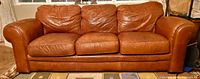 front view of brown leather 3-seat sofa showing overall design and wear