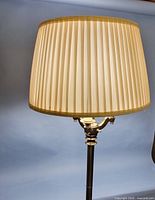 Upper portion of brass floor lamp with pleated shade