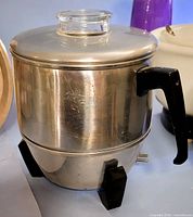 Front angle of aluminum Mirro electric popcorn popper showing glass lid and black handle
