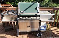Front view of Weber Summit gas grill with side shelves and propane tank