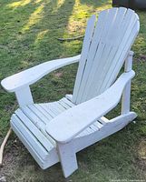 Front angled view of white wooden Adirondack chair on lawn