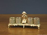 Full view of gold-tone metal lipstick holder front side