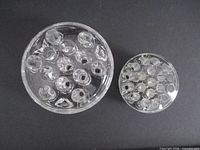 Top view of both glass flower frogs, showing size difference and hole arrangement