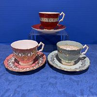 Group shot of three Aynsley crocus cup and saucer sets in red, pink, and pale aqua