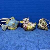 group shot of three cloisonné ornaments: fish, duck, heart with ribbons