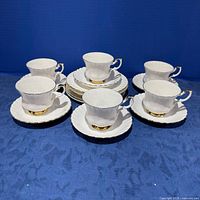 Six teacup, saucer and plate sets displayed, center stack of plates visible
