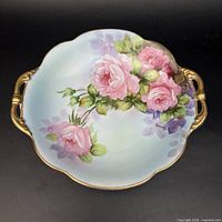 Full view of scalloped double-handled plate with hand painted roses and gilt trim