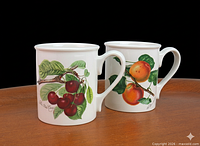 Front view of both mugs showing cherry and apricot illustrations