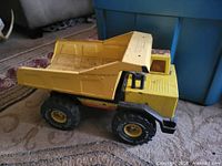 Left side view of yellow Tonka dump truck showing full profile and large rubber tires