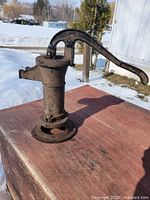 Side view of cast iron hand pump head on wooden surface