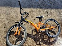 Full view of bicycle lying on ground, shows frame color, wheel size, seat damage