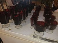 All 24 ruby red stemmed glasses grouped on surface