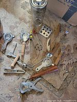 Group view of all bar tools spread on rug including stainless shaker and assorted utensils