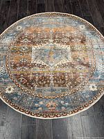 Full view of round rug on dark floor shows overall colour palette and condition