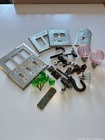 All items laid out on white surface: embossed switch plates, glass knobs, cast iron pieces, porcelain rollers, label plate