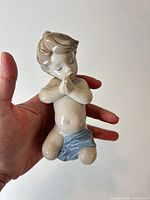 Front view of Lladró porcelain praying child figurine held in hand
