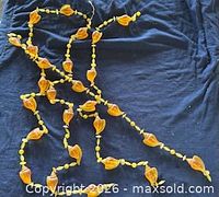 Four intertwined acrylic seashell bead strands displayed on dark fabric