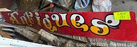 Front view of red wooden sign with “Antiques” lettering