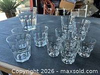 Group of six large and ten small clear faceted tumblers on table