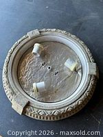 Top view of round flush mount fixture base showing three bulb sockets and decorative edge