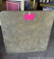 Front view of square folded card table showing green mottled laminate surface