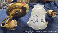 Two brass metal fixtures with ceramic sockets and frosted floral glass shade