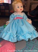 Front view of Miss Muffet doll in blue polka-dot dress holding green cup