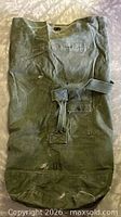 Full view of olive drab duffel bag front with strap, pocket, US marking