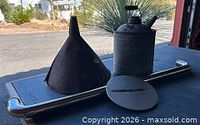Oil can, funnel, and wheel cap grouped on surface