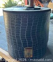 Front view showing cylindrical shape, faux crocodile texture and latch