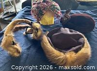 Group shot of all four items: three hats and mink fur clips on blue surface