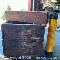 wooden ammunition crate front with removable lid and yellow flashlight beside