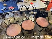 Front view of three wrought iron chairs showing overall design and seat condition