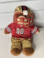 Front view of plush bear in 49ers uniform with helmet and jersey