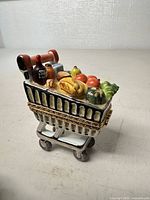 Front angle of Limoges shopping cart trinket box showing groceries and clasp