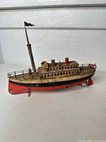 Side view of full tin steamboat showing hull, deck, smokestacks, mast