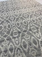Close-up of rug showing beige and light grey geometric oval pattern