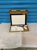 Light pad standing in open box with cable and foam inserts visible