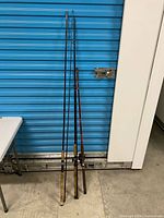 Three fishing rods leaning against wall