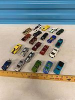 Full layout of approximately 22 toy cars with ruler for scale