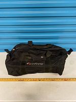 Overall view of duffel front, logo visible, ruler for scale