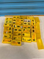 Group of roughly thirty yellow slide boxes on table with ruler for scale
