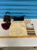 All five handbags and keychain laid out with ruler for scale