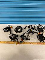 Six coiled AV cables laid out for overview with yardstick for scale