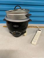Oster rice cooker with steamer tray, lid and power strip