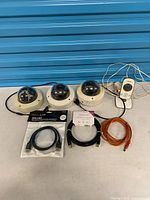 All items laid out: three dome cameras, VTech camera, packaged HDMI cable, orange cable, USB cable