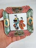 Front view of square porcelain dish with handpainted geisha scene and multicolour border